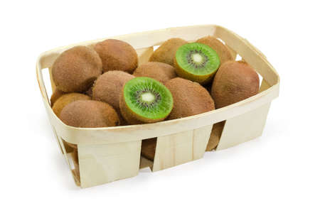 Ripe fuzzy kiwifruits with one fruit cut in half in the wooden basket on a white backgroundの写真素材