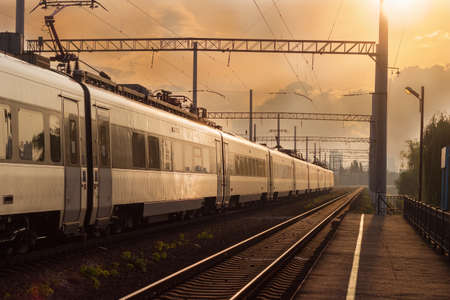 Section of the railroad in the city with moving high-speed inter-city train on the sunset background