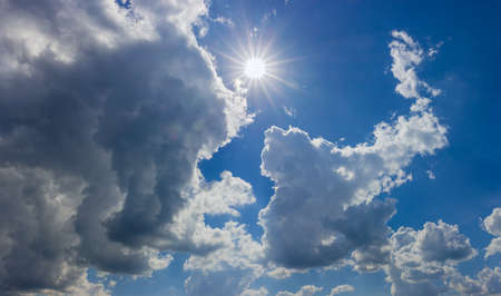 Panorama of a fragment of the sky with sun, cumulus and storm clouds