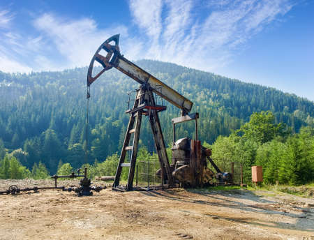 Pump-jack pumping petroleum on oil well located in the Carpathian Mountainsの写真素材