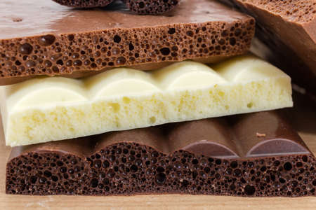 Background of texture of the transversal splits of dark, milk and white aerated chocolate blocks close-upの写真素材