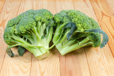 Two branches of the fresh broccoli close-up on a light colored wooden rustic tableの写真素材