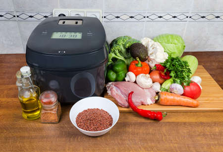 Modern electric automatic smart household multi-cooker among of various raw foods on a cook tableの写真素材