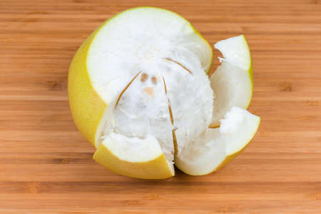 Ripe pomelo fruit with yellow peel after being cut on a wooden cutting board close-upの写真素材