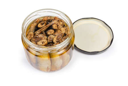 Smoked sprats preserved in vegetable oil in small glass jar with open lid on a white backgroundの写真素材