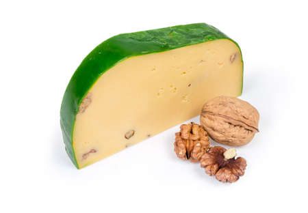 Piece of semi-hard cheese with wax green protective covering and  addition of a crushed walnut kernels, whole walnut fruit and peeled walnut kernels on a white backgroundの写真素材