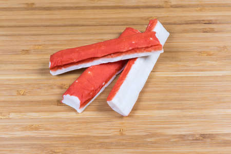 Several crab sticks on a wooden bamboo cutting board close-upの写真素材
