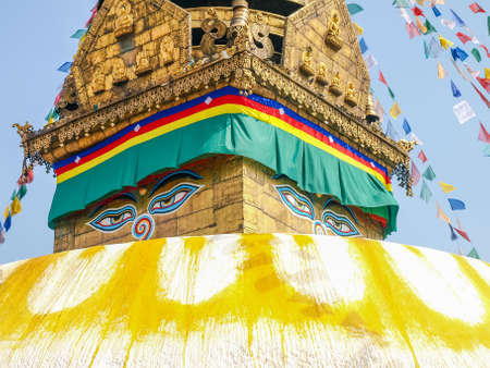 Fragment of Swayambhunath Stupa with Buddha's eyes in base of spire on a background of prayer flags and sky close-up, Kathmandu, Nepalの写真素材