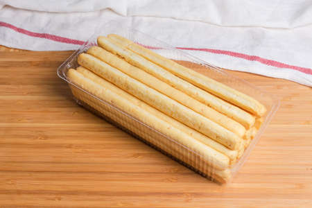 Breadsticks with sesame seeds also known as grissini in transparent plastic container on a bamboo...