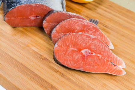 Uncooked fresh salmon steaks on a wooden bamboo cutting board close-upの写真素材