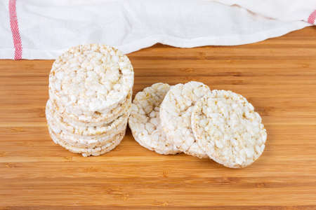 Dry round puffed crispbreads made from brown rice on a bamboo wooden surfaceの写真素材