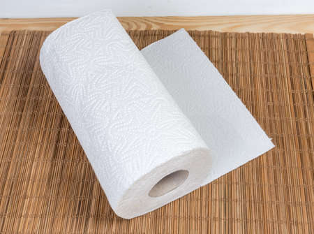 Roll of two-ply paper towels with tear-off sheets on the wooden bamboo table matの写真素材