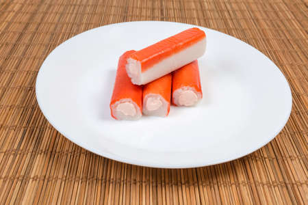 Crab sticks stuffed with processed cheese spread on the white dish on a bamboo table matの写真素材