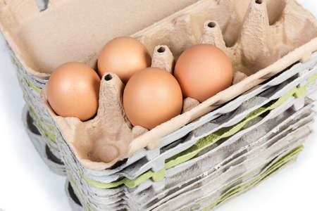 Several brown chicken eggs in upper egg carton of the folded stack from similar packaging made of...