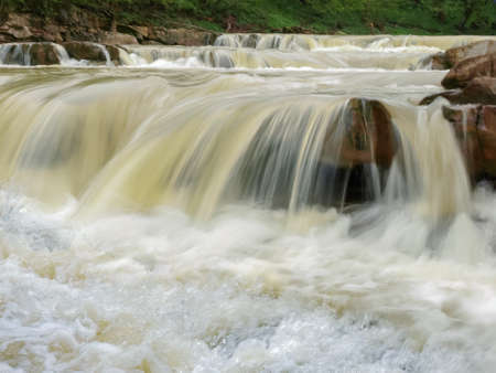 Fragment of the multi-cascades low-level waterfall on a mountain river after rains in the Carpathian...