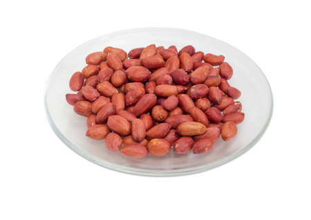 Dry roasted peanuts peeled from shells on glass dish on a white background