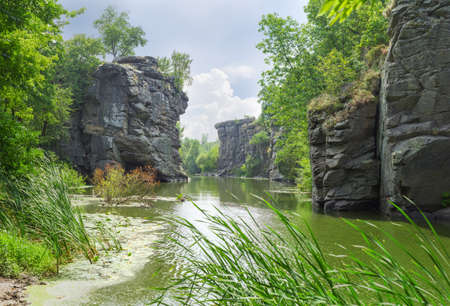 Calm river flowing in canyon with overhanging cliffs on two banks, Buky Canyon, Ukraine