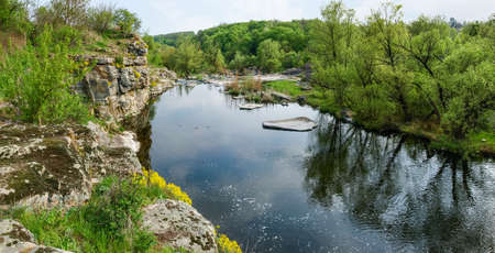 Panoramic view of the river section with rocky steep bank and forest on opposite bank in springtime. Hirs'kyi Tikych river, Ukraineの写真素材