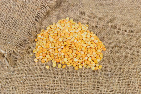 Small pile of raw yellow variety of the split peas on a sackcloth