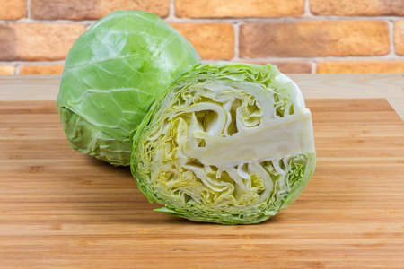 Whole and half of head of the young white cabbage on the wooden bamboo cutting board