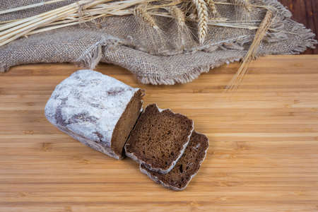 Partly sliced loaf of the dark brown bread made of rye and wheat flour and different addition on a...