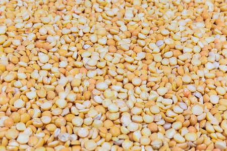 Raw yellow variety of the split peas scattered on surface close-up in selective focus