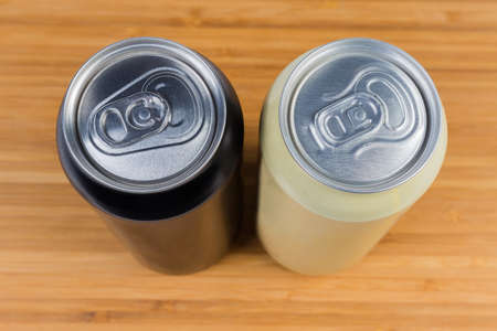 Top view of two sealed beverage cans on wooden surface