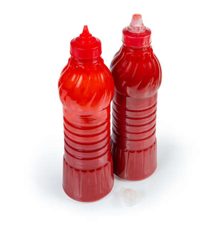 Tomato sauce in one open and one closed red plastic bottles,  one lid separately on a white backgroundの写真素材