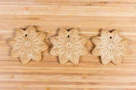 Shortbread cookies in the form of stars, laid out in row on wooden surface, top view