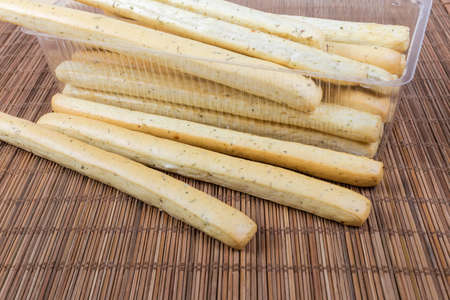 Breadsticks with Italian herbs seasoning, also known as grissini, in transparent plastic container...