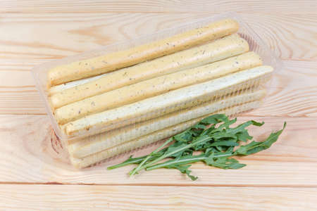 Breadsticks with Italian herbs seasoning, also known as grissini, in transparent plastic container...