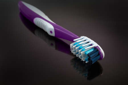 Modern traditional toothbrush on a dark reflective surface close-up in selective focus
