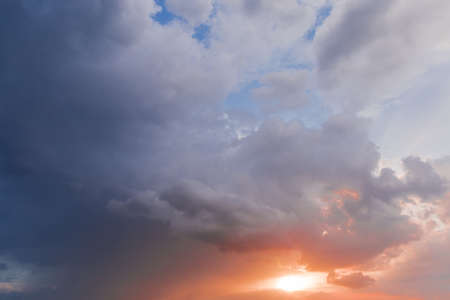 Fragment of the sky with cumulus clouds and sun at sunset
