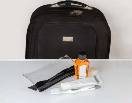 Toiletry kit for oral hygiene and plastic men's travel toiletry bag on a light surface on a blurred background of the suitcaseの写真素材