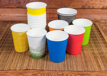 Empty disposable paper cups different sizes and colors on the bamboo table mat on rustic tableの写真素材