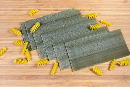 Dried uncooked green lasagna pasta sheets with addition of spinach in the dough among spiral pasta...