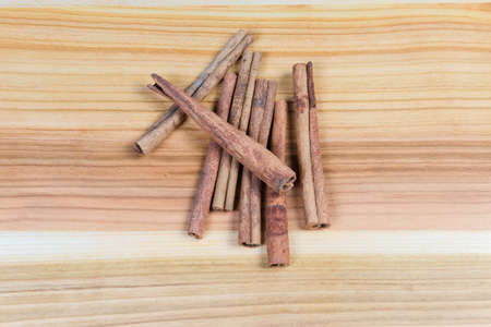 Several dried cinnamon sticks on the wooden surface, top viewの写真素材