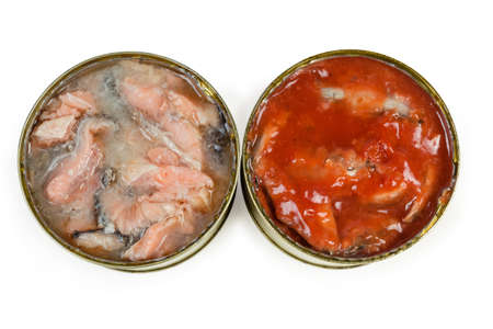 Canned salmon in its own juice and canned fish with tomato sauce in two open tin cans on a white...