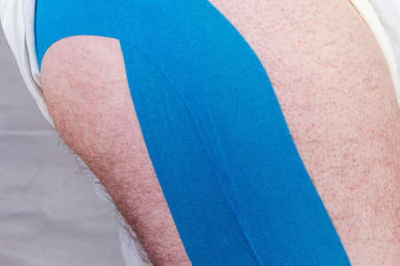 Blue elastic therapeutic tapes, also known as kinesiology tapes pasted on the male leg, fragment close-upの写真素材