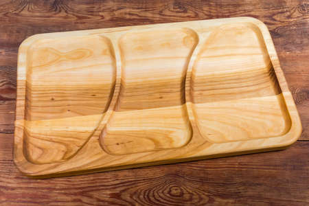 Empty rectangular compartment dish with three departments made with hardwood on the old rustic table