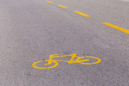 Section of asphalt road with road marking of sign of the bike path and dividing dashed line