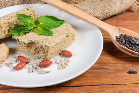 Crumbly sunflower halva with peanuts addition, separately mint leaves, sunflower seeds, peanuts on...