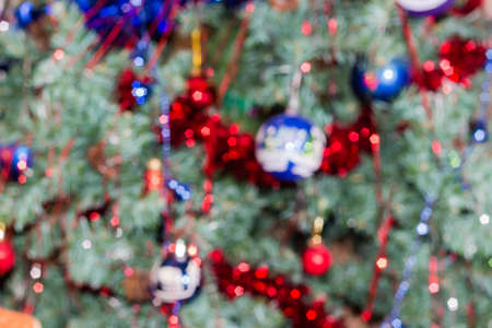 Background of blurred image of the Christmas tree with Christmas lights indoors 