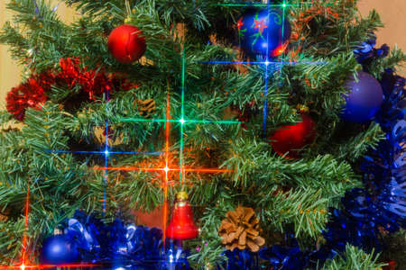 Fragment of the artificial Christmas tree with traditional decorations and electric garland of varicolored Christmas lights indoors, background 
の写真素材
