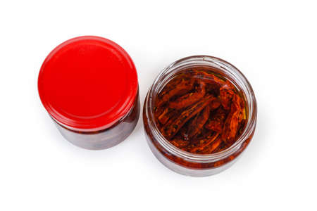 Sun-dried red tomatoes preserved in olive oil in small open glass jar and closed jar on a white background, top view
の写真素材