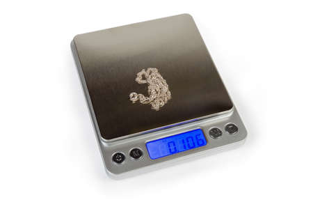 Professional high precision digital table top scales with LCD display with blue backlight and stainless steel platform with silver jewelry on her on a white backgroundの写真素材
