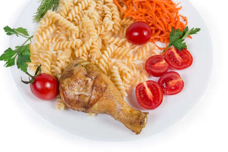 Fried crispy chicken leg with side dish of boiled spiral pasta and fresh vegetables on the white dish on a white background, top viewの写真素材