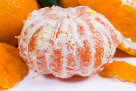 Whole mandarin orange peeled from peel against the other tangerines close-up in selective focusの写真素材