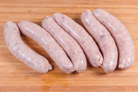 Uncooked pork sausages for grilling in natural casing on the bamboo wooden cutting board
の写真素材