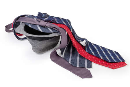 Several men's knitted patterned ties different colors and widths lying on the inverted cotton lightweight hat in fedora style on a white backgroundの写真素材